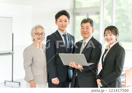 パソコンを使う高齢者と若いビジネスマン（家族経営・後継者・事業継承・跡取り・売却・買収・世代交代） 121417500