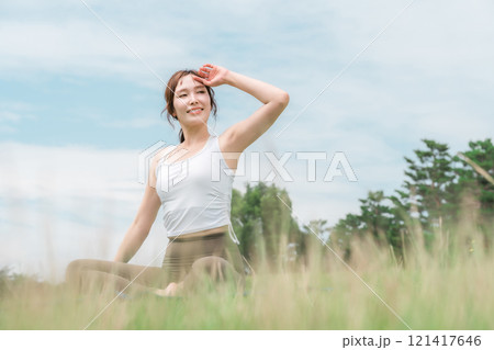 草原の中でヨガ・ストレッチ・ピラティス・ボディケアをする女性(ヘルスケア・ダイエット・健康維持) 121417646