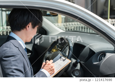 チェック表を使って車の査定・見積もりをするセールスマン・査定士の手元 121417690