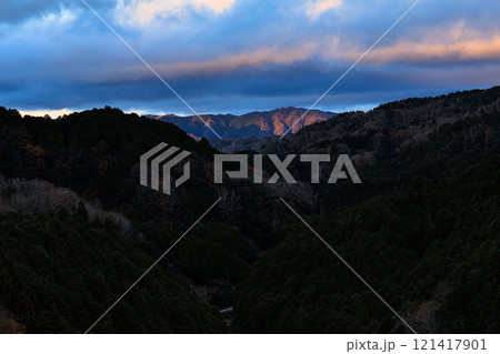2024年　年末真冬の布目ダム夕景　布目川下流域遠景の山を照らす夕日 121417901