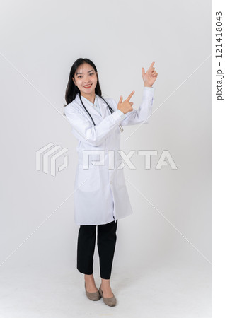 A positive Asian female doctor pointing to the side as if recommending an option, studio background. A positive Asian female doctor pointing to the side as if recommending an option, studio background. 121418043