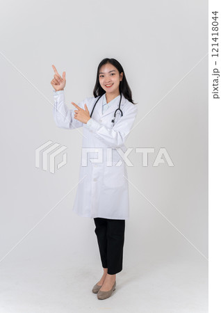 A positive Asian female doctor pointing to the side as if recommending an option, studio background. A positive Asian female doctor pointing to the side as if recommending an option, studio background. 121418044