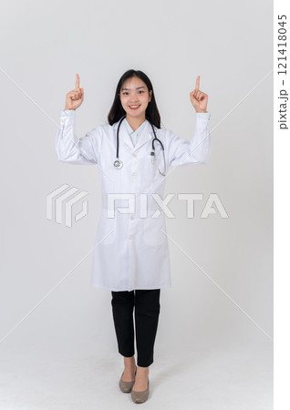 A positive Asian female doctor pointing her finger at an empty space as if recommending an option. A positive Asian female doctor pointing her finger at an empty space as if recommending an option. 121418045