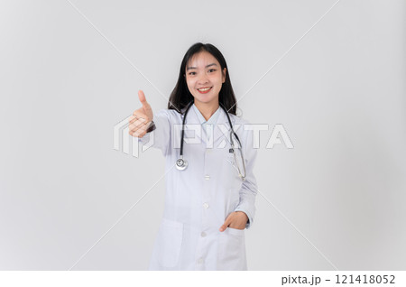 A female doctor stands against a studio background, smiling and giving a thumbs up to the camera. A female doctor stands against a studio background, smiling and giving a thumbs up to the camera. 121418052