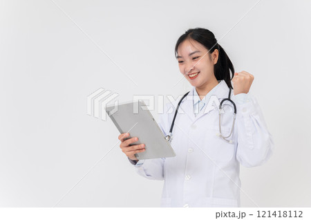 A smiling Asian female doctor in a white gown uniform using her digital tablet on studio background. A smiling Asian female doctor in a white gown uniform using her digital tablet on studio background. 121418112