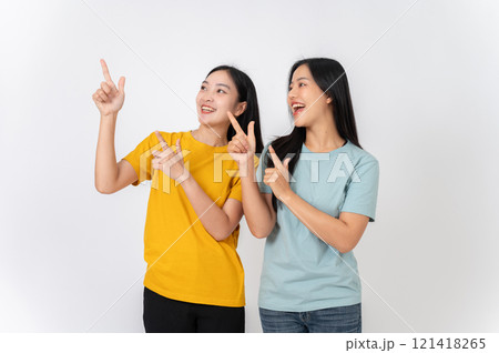Two cheerful females pointing their finger upward at an empty space, recommending a special offer. Two cheerful females pointing their finger upward at an empty space, recommending a special offer. 121418265