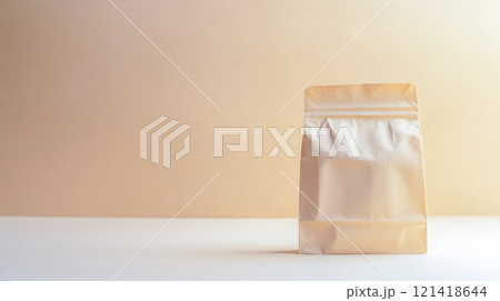 Small paper bag standing on white table against cream background 121418644