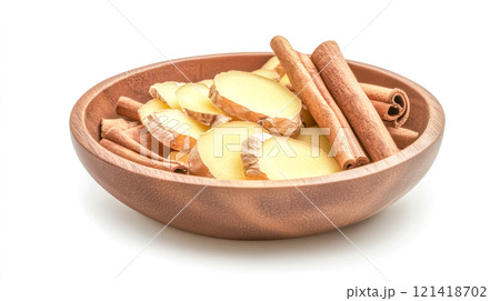 Fresh ginger slices and cinnamon sticks resting in wooden bowl 121418702