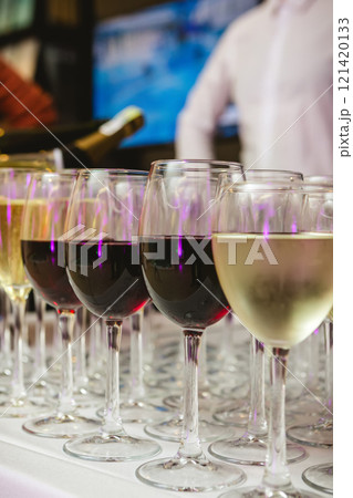 A beautifully arranged collection of wine glasses filled with red and white wines, set on a white tablecloth 121420133