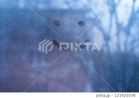 A painted smiling smiley face on a window with drops. The concept of happy mood and emotions 121420336
