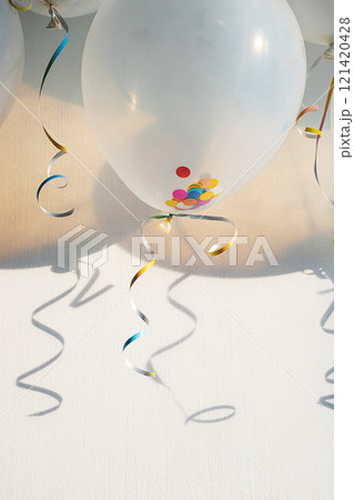 Balloons with colorful confetti and ribbons casting shadows on a wall. Celebration concept Balloons with colorful confetti and ribbons casting shadows on a wall. Celebration concept 121420428