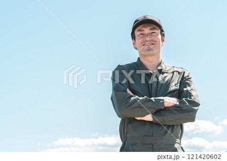青空の下にいるつなぎ姿の作業員・整備士の男性 青空の下にいるつなぎ姿の作業員・整備士の男性 121420602