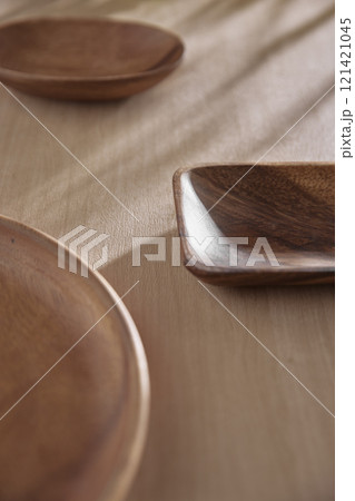 Various tableware on a soft wood-toned table background with sunlight shining through. Various tableware on a soft wood-toned table background with sunlight shining through. 121421045
