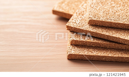 Cork boards stacked on wooden surface, showcasing their textured surface and natural color. Ideal for insulation or flooring applications.  Green Building Materials concept 121421945