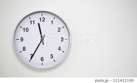 Minimalist White Clock with Silver Frame Striking 11.35/23.35 on White Background. Perfect for Time Management and Corporate Campaigns Minimalist White Clock with Silver Frame Striking 11.35/23.35 on White Background. Perfect for Time Management and Corporate Campaigns 121422199