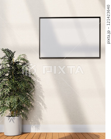 A minimalist interior with a blank frame on a wall beside a potted plant, with warm wooden flooring and soft light casting shadows. 3D rendering 121423640