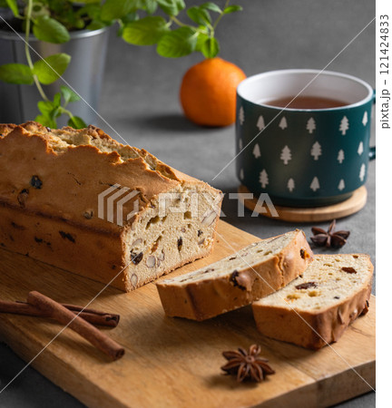Spicy pie with fruits, nuts and spices on a wooden board, on a dark background 121424833