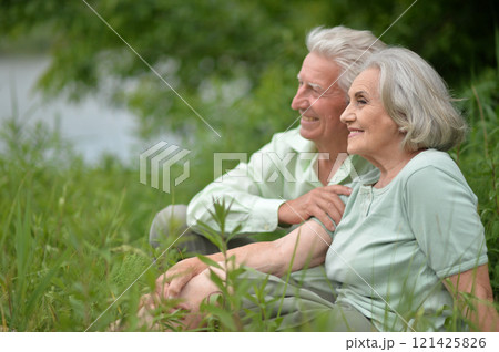 Portrait of senior couple sitting on the grass in the park 121425826