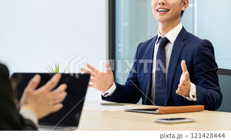 笑顔で対話・商談をする男性ビジネスマン 121428444