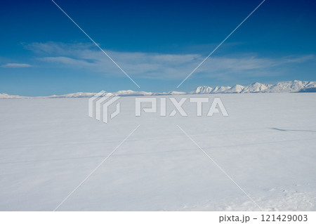 冬の晴れた日の雪原と山並み 121429003