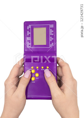 Close-up of a purple handheld game console in female hands isolated on white background Close-up of a purple handheld game console in female hands isolated on white background 121429731