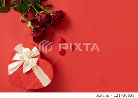Valentine's day romantic gift, bouquet of red roses and heart shaped chocolate sweets on red background. View from above. Greeting card. Copy space. 121430639