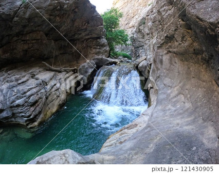 Aksu waterfall with fast flowing and clear water, surrounded by rocks 121430905