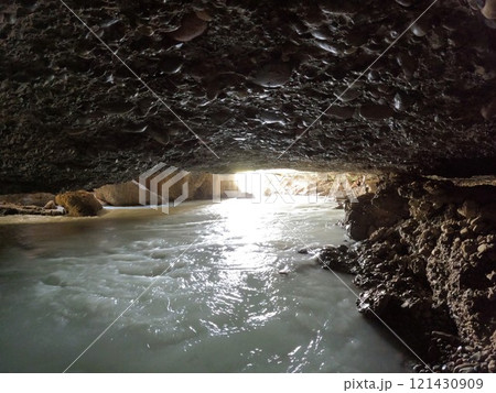 view from the cave with the underground river Aksu with white water, stone vaults, sunlight illuminates the entrance to the cave view from the cave with the underground river Aksu with white water, stone vaults, sunlight illuminates the entrance to the cave 121430909