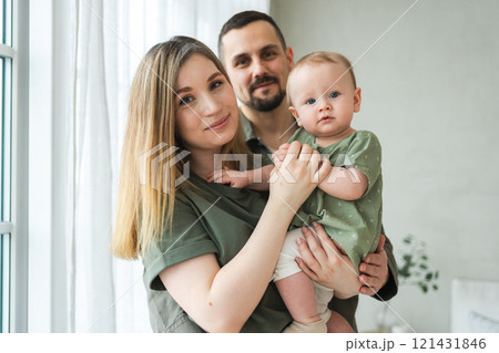 Happy family at home. Mother father holding little toddler child. Mom dad baby girl relax playing having fun together. Woman man hugging embracing baby with love care. Parent of breast feeding baby 121431846