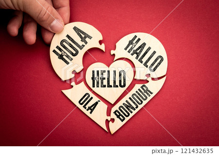 Hello in different languages. Wooden puzzle in the shape of a heart on a red background Hello in different languages. Wooden puzzle in the shape of a heart on a red background 121432635