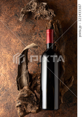 Bottle of red wine and old weathered snags on a brown vintage background. 121433387