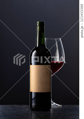 Bottle and glass of red wine on a black background. 121433389