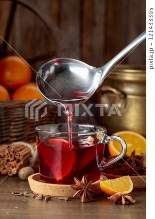 Mulled wine is poured into a glass cup. 121433395