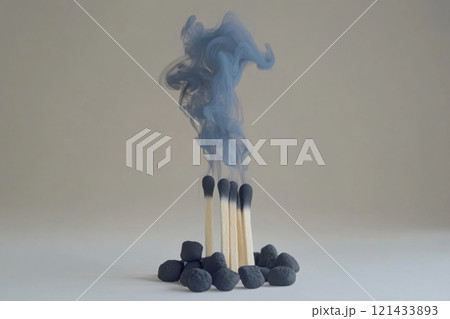 Smoke from burnt matches rising above scattered pebbles in minimalist setting 121433893