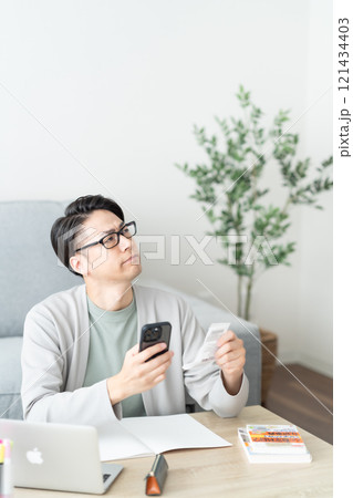 レシートを見ながら帳簿用の支出の仕分けをする若い男性 121434403