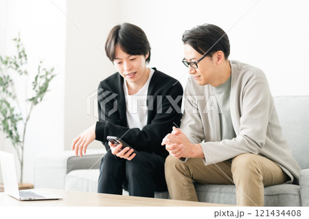 スマホを見ながら談笑する若い男性 121434408