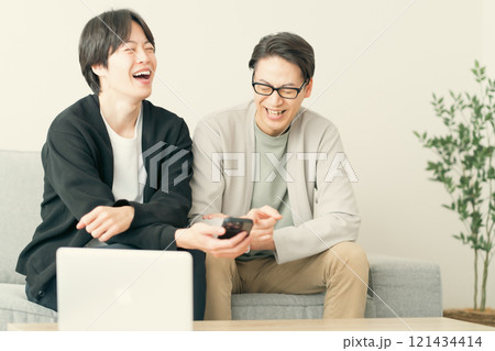 スマホを見ながら談笑する若い男性 121434414