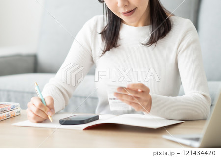 レシートを片手に帳簿をつけるミドル女性 顔無し レシートを片手に帳簿をつけるミドル女性 顔無し 121434420