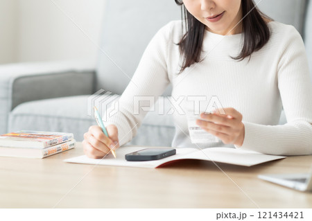 レシートを片手に帳簿をつけるミドル女性 顔無し レシートを片手に帳簿をつけるミドル女性 顔無し 121434421