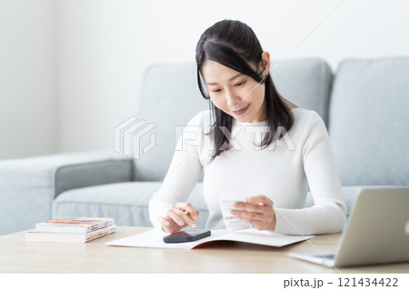 レシートを片手に帳簿をつけるミドル女性 レシートを片手に帳簿をつけるミドル女性 121434422