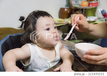 【離乳食を食べる髪を結んだ赤ちゃん】 【離乳食を食べる髪を結んだ赤ちゃん】 121435231