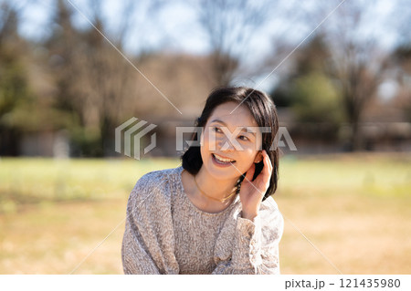 公園の芝生でくつろぐミドルの女性 公園の芝生でくつろぐミドルの女性 121435980