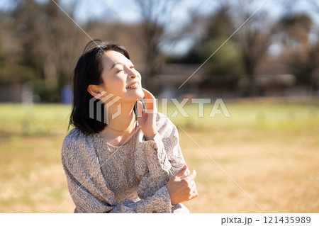 公園の芝生でくつろぐミドルの女性 121435989