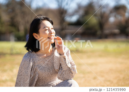 公園の芝生でくつろぐミドルの女性 121435990