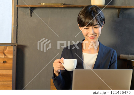 カフェでコーヒーを飲みながらパソコンも見る女性 カフェでコーヒーを飲みながらパソコンも見る女性 121436470
