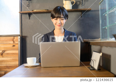 カフェでパソコンも使って仕事中の女性　 121436615
