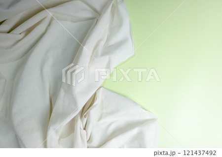 Top view of crumpled white fabric on a colored background 121437492