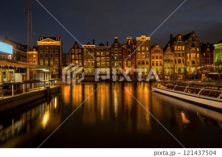 Panoramic view of facades of colorful illuminated Amsterdam houses reflecting in the river canal with night scene background 121437504