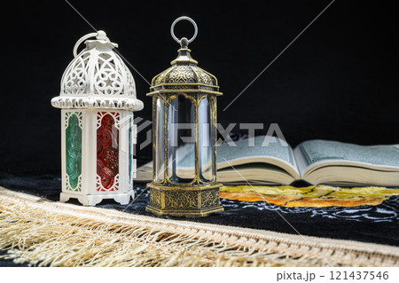 Arabic lanterns and Quran on a prayer mat with a black background. Decoration for Muslim holidays celebration 121437546