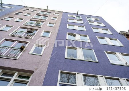 Low angle view of several tall buildings in a row with old style and have many windows of geometric shapes with clear sky background Low angle view of several tall buildings in a row with old style and have many windows of geometric shapes with clear sky background 121437598